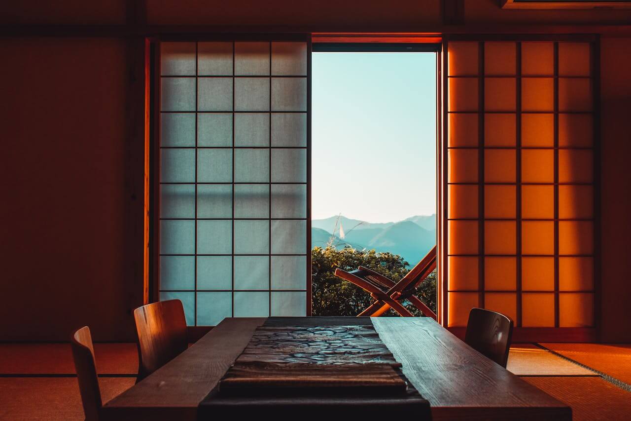 Ryokan: Everything You Need to Know Before Your First Stay A serene Japanese room featuring shoji screens and a mountain view, illuminated by warm lighting.