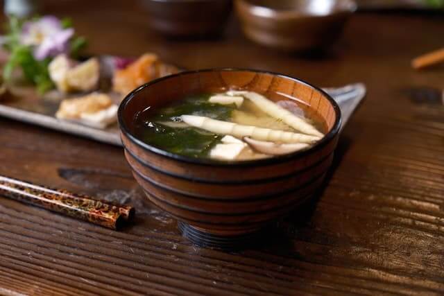 How the World's Longest-Living Nation Keeps Its Healthy Food Culture Alive A wooden bowl of dashi-based soup with chopsticks