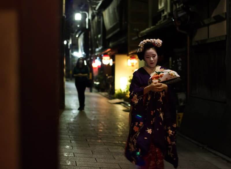 The Geisha That Never Existed — And What She Was Replaced With Maiko in kimono walking through narrow Gion alley Kyoto Japan
