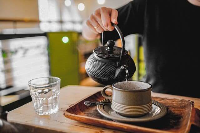 The Gut-Brain Axis Japan Wove Into Everyday Life Person pouring hot water from a cast iron kettle into a cup, morning ritual