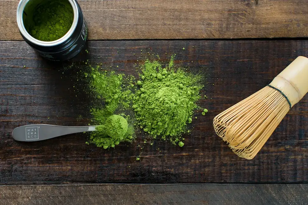 What I Learned Before Making Matcha at Home Matcha powder and bamboo whisk on a wooden table