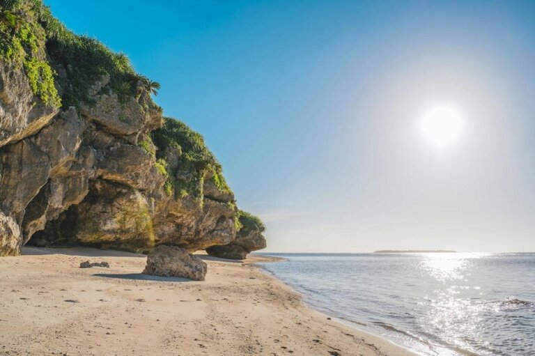 A beach in Okinawa with a large cliff right next to it.