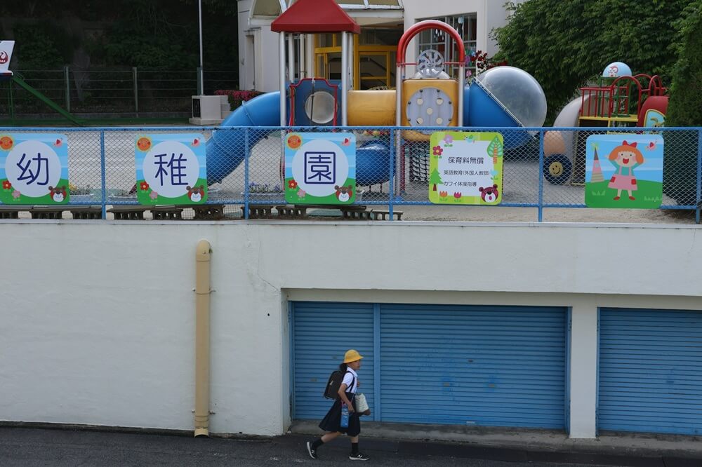Why Japanese Children Walk to School Alone Young Japanese girl in yellow school hat running near a playground